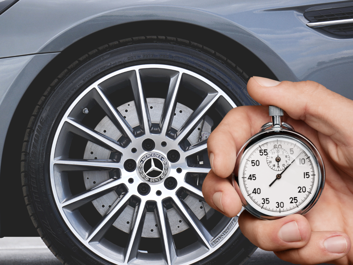 Hand hält eine Stoppuhr neben einer glänzenden Mercedes-Benz-Felge.